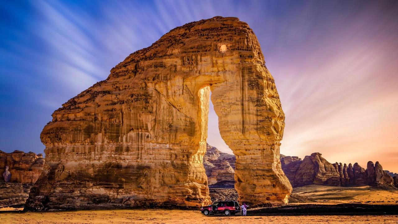 Intercontinental Dar Al Iman Madinah By Ihg Hotel Medina Kültér fotó The photo depicts a striking rock formation, characterized by a large archway that has been sculpted by natural processes. The landscape around the formation features sandy terrain and rugged terrain, typical of desert environments. In the foreground