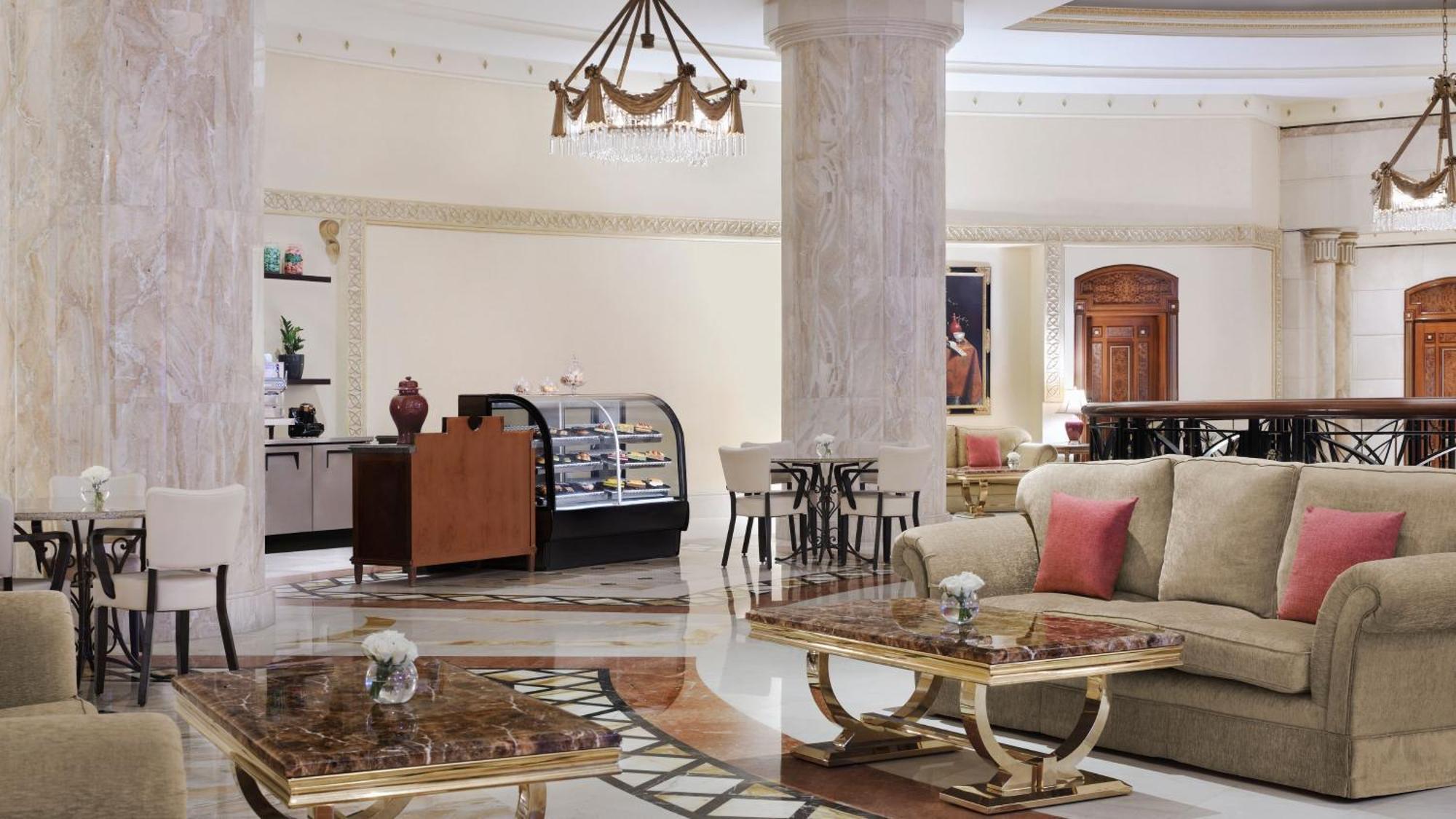 Intercontinental Dar Al Iman Madinah By Ihg Hotel Medina Kültér fotó The photo shows a luxurious hotel lobby or lounge area. It features elegant marble floors and tall columns. There are comfortable seating arrangements with a sofa and stylish tables that have marble tops. A display case for pastries or refreshments i