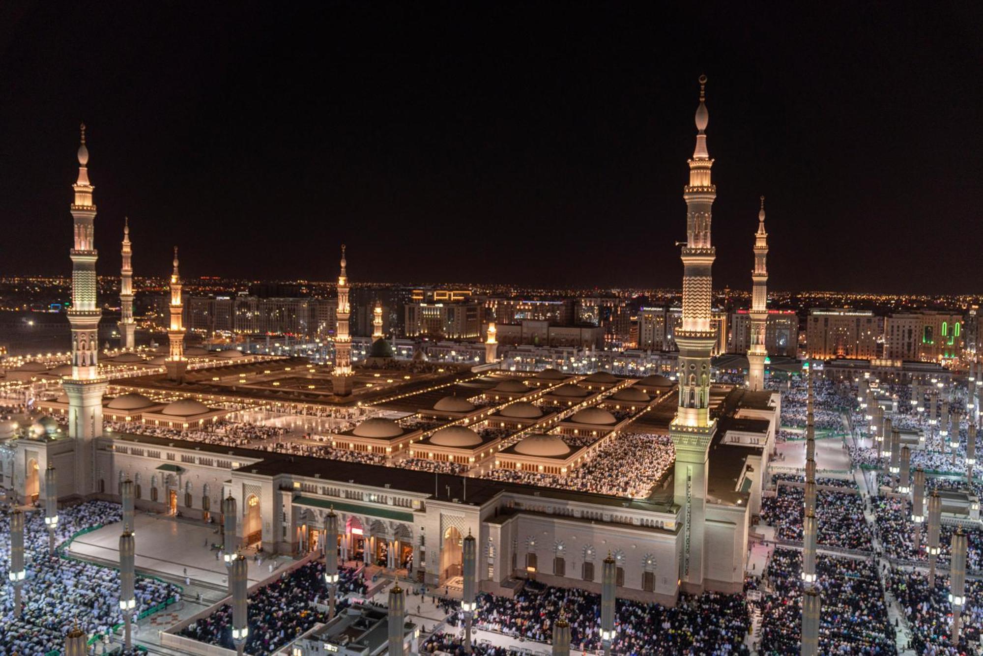 Intercontinental Dar Al Iman Madinah By Ihg Hotel Medina Kültér fotó The photo shows a panoramic view of a large mosque complex illuminated at night. It features tall minarets with lights, a vast courtyard filled with people, and a beautifully lit architectural design. The overall ambiance suggests a significant space