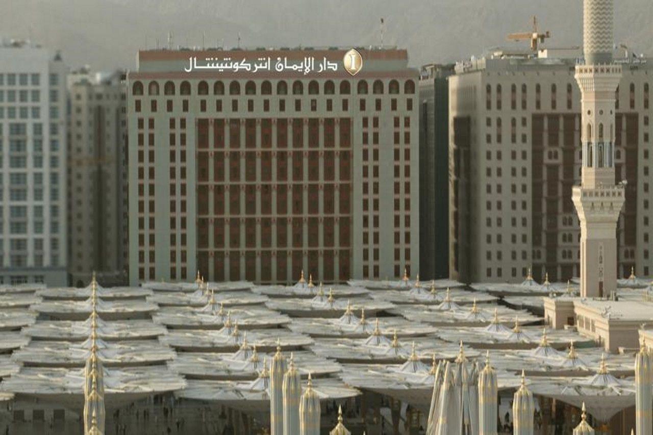 Intercontinental Dar Al Iman Madinah By Ihg Hotel Medina Kültér fotó The photo shows a view of a large building with a modern architectural design, which appears to be a hotel or a commercial establishment. In front of the building, there are several large white canopies that provide shade, likely in a public space or